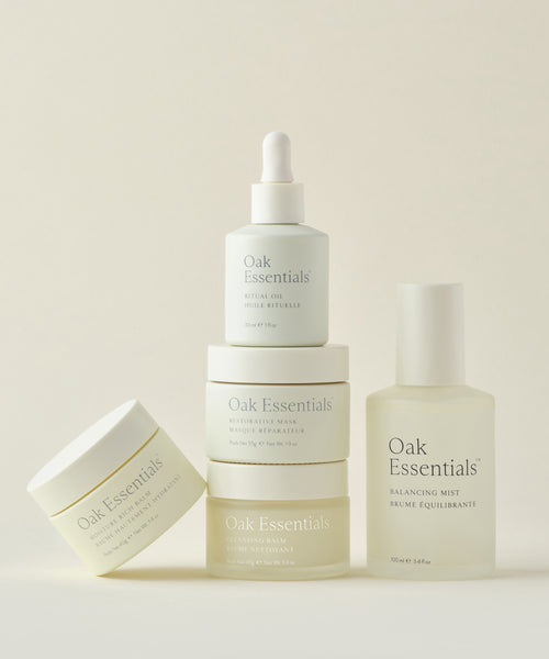 The Routine by Oak Essentials, featuring jars, a dropper bottle, and a spray bottle in minimalist packaging, is arranged on a neutral background to showcase the 5-step regimen for glowing skin.