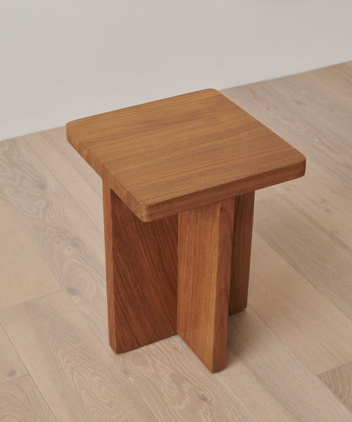 The Outdoor Marin Square Side Table is a small, square teak piece with a minimalist design, featuring an intersecting base and smooth finish—ideal as an elegant side table for any space.