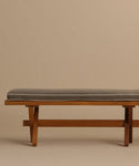 The Outdoor Garden Dining Bench features clean lines, tapered legs, and a simple solid teak design. It includes a rectangular gray Tempotest fabric cushion on top with a beige background.