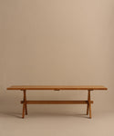The Outdoor Garden Dining Table features a long, minimalist teak design with a rectangular top and simple trestle legs, shown against a plain beige background.
