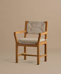 The Outdoor Montecito Dining Arm Chair features solid teak, a light beige cushioned seat, and a textured patterned fabric backrest, displayed against a plain beige background.
