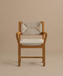 The Outdoor Montecito Dining Arm Chair features a solid teak frame, a light beige geometric woven backrest, and a Tempotest fabric cushion, shown here against a plain taupe background.