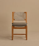 The Outdoor Montecito Dining Chair features a geometric woven ECOLENE backrest, a gray cushioned seat, and a wooden frame, displayed against a plain beige background.