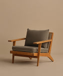 The Outdoor Vista Chair is a modern teak chair with angled legs, wide armrests, ECOLENE woven sides, and thick dark gray Tempotest cushions set against a neutral beige background.
