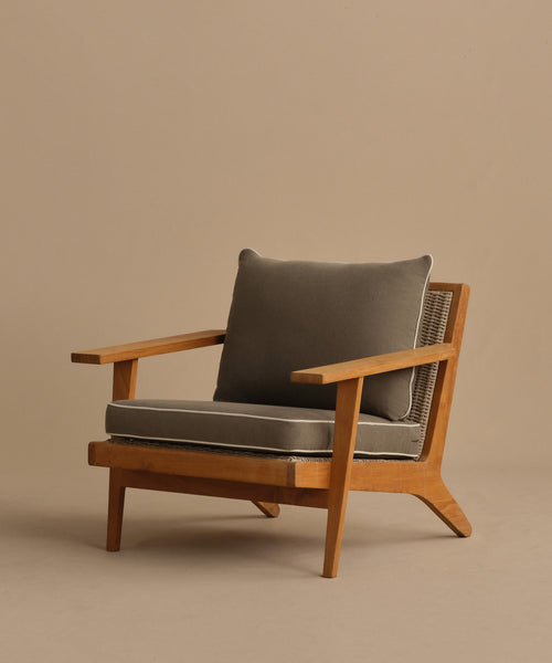 The Outdoor Vista Chair is a modern teak chair with angled legs, wide armrests, ECOLENE woven sides, and thick dark gray Tempotest cushions set against a neutral beige background.