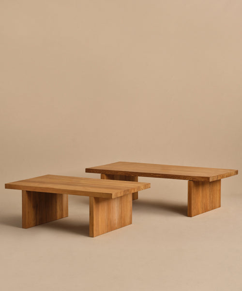 Two low, rectangular Outdoor Vista Coffee Tables with simple, modern design feature thick tops and sturdy block legs. Placed side by side on a beige floor and background, they add style to any outdoor space.