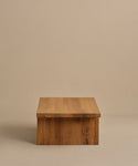 The Outdoor Vista Coffee Table features a minimalist rectangular teak design with a smooth flat top, showcased against a plain beige background.