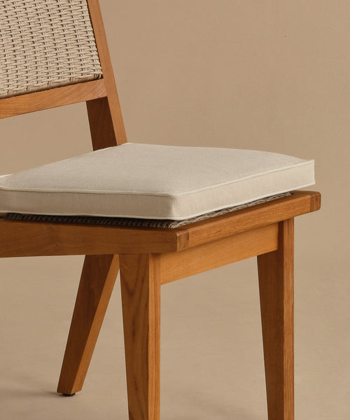 A close-up of the Outdoor Vista Dining Chair, featuring a solid teak frame, woven ECOLENE backrest, and beige seat cushion, set against a plain beige background.