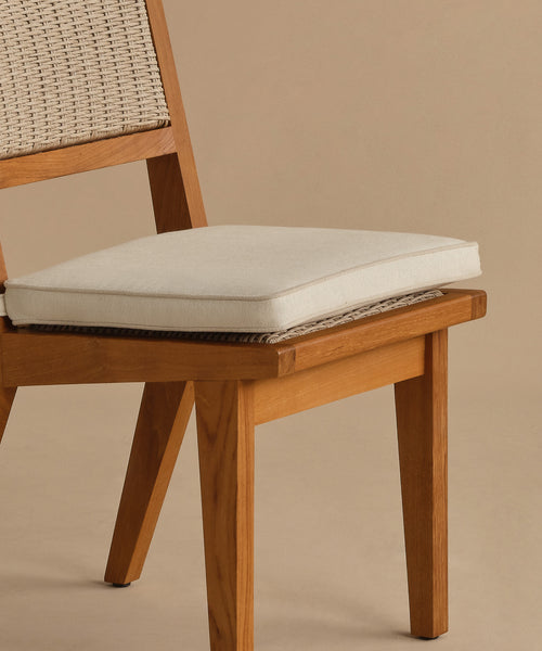 A close-up of the Outdoor Vista Dining Chair, featuring a solid teak frame, woven ECOLENE backrest, and light seat cushion, set against a plain beige background.
