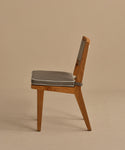 Side view of the Outdoor Vista Dining Chair in solid teak with a grey cushioned seat, angled backrest, and ECOLENE woven detail on the upper back, set against a plain beige background.