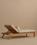 The Outdoor Vista Lounge Chair features a teak frame, light beige cushions, and an adjustable backrest, creating a durable and stylish outdoor seating option shown against a plain beige background.