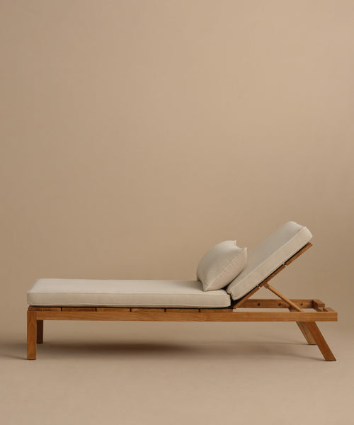 The Outdoor Vista Lounge Chair features durable teak construction and a white cushion, making it perfect for relaxing in style.