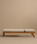 The Outdoor Vista Lounge Chair, featuring clean lines and a minimalist teak frame with light-colored seat cushions, is showcased against a plain beige background, highlighting its modern design and durable appeal for outdoor living.