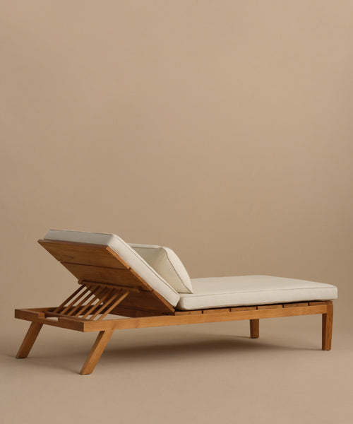 The Outdoor Vista Lounge Chair features a durable teak frame, white cushions, and an adjustable backrest, set against a plain beige background.