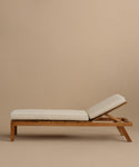 The Outdoor Vista Lounge Chair features light beige cushions and a slightly reclined backrest, shown in profile against a plain beige background, highlighting the chair’s elegant, durable, and comfortable design.
