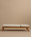 The Outdoor Vista Lounge Chair, a minimalist wooden seat with two cream cushions, sits against a plain beige background, embodying the simple and modern design of durable outdoor furniture.
