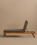 The Outdoor Vista Lounge Chair, featuring a cushioned seat, adjustable backrest, and minimalist teak design, is shown in side profile against a plain beige background—perfect for stylish outdoor lounging.