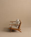 The Outdoor Vista Sofa, featuring light beige Tempotest fabric cushions and a modern wooden frame, is displayed in profile against a plain beige background, highlighting its minimalist and elegant design.