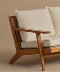 A close-up of the Outdoor Vista Sofa features light Tempotest fabric cushions, a beige backdrop, and highlights the armrest, angled legs, and textured seat details.