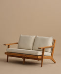 The Outdoor Vista Sofa features a wooden frame, angled legs, light Tempotest fabric cushions, and woven cane accents on the sides, displayed against a plain beige background.