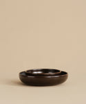 Two Pacific Breakfast Bowls in dark brown stoneware are nested together on a beige background, showcasing their minimalistic, elegant design and rich chocolate tones.