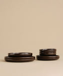 A pair of Pacific Dinner Plates in dark brown stoneware, neatly stacked against a beige background—ideal for upgrading your dinnerware collection.