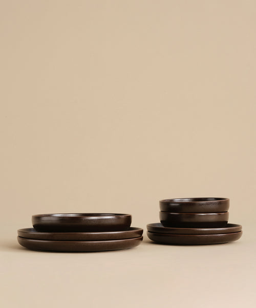 A pair of Pacific Dinner Plates in dark brown stoneware, neatly stacked against a beige background—ideal for upgrading your dinnerware collection.