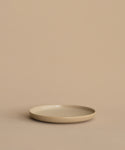 A Pacific Salad Plate, round and beige, rests on a matching surface with a beige background, forming a minimal and neutral scene.