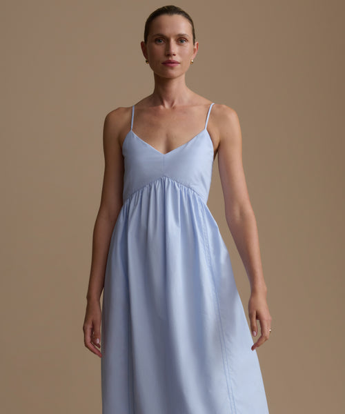 Woman wearing a light blue dress against a beige background