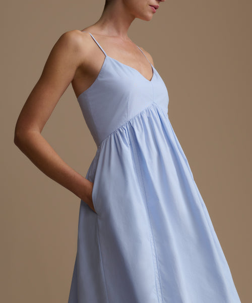 Woman wearing a light blue dress against a beige background