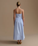 Woman wearing a light blue dress with thin straps on a beige background