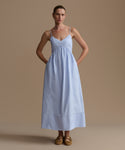 Woman wearing a light blue dress against a beige background