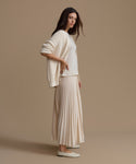 Woman wearing an ivory outfit against a plain background