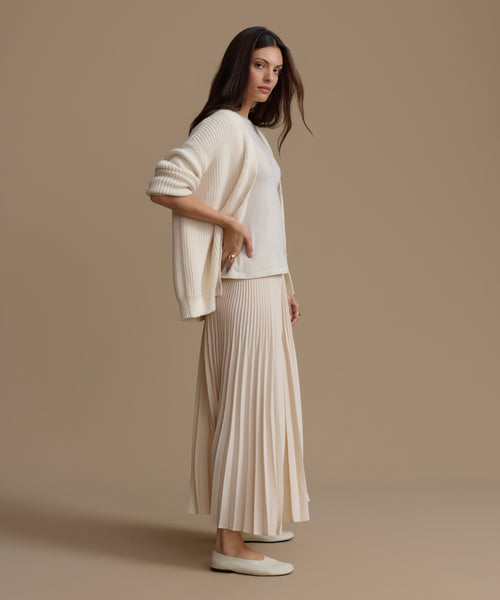 Woman wearing an ivory outfit against a plain background