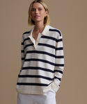 Woman wearing a black and white striped sweater over a white shirt on a beige background