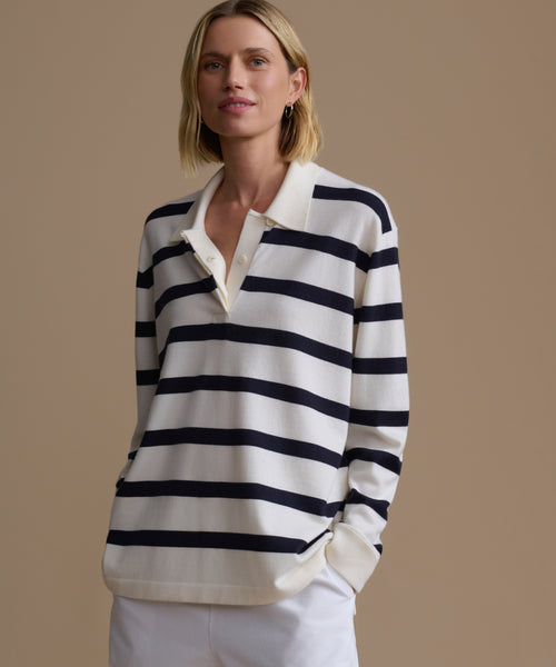 Woman wearing a black and white striped sweater over a white shirt on a beige background