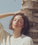 Thumbnail for video: Woman wearing a cream cable knit sweater on a beach