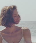 Thumbnail for video: Woman in a white dress standing on a beach.