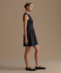 Woman wearing a black sleeveless dress against a beige background