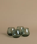 Recycled glass cups against a beige background.