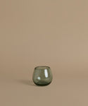 Recycled glass cup against a beige background.