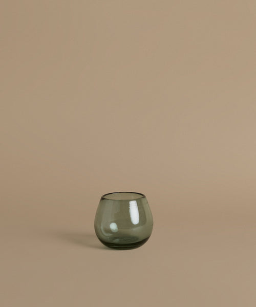 Recycled glass cup against a beige background.