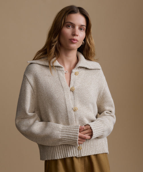 Woman wearing a beige knitted cardigan against a brown background