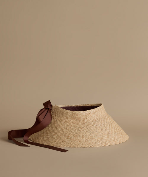 Straw visor with a brown ribbon on a beige background