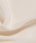 Close-up of the Silk Sloane Shirt showcases smooth, sandwashed silk in a cream shade, featuring gentle folds and a soft, lustrous texture.