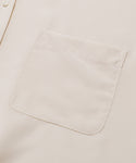 Close-up of the Silk Sloane Shirt in cream-colored sandwashed silk, showing a single chest pocket and part of an ivory button on the left side.