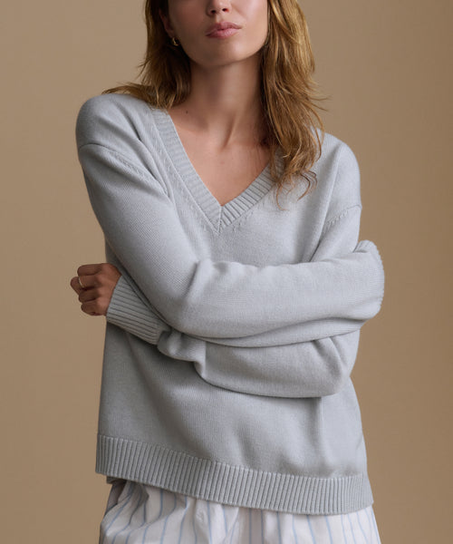 Woman wearing a light blue sweater against a beige background