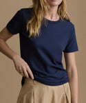 Person wearing a navy blue t-shirt and beige pants on a brown background