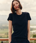 Woman wearing a navy blue t-shirt and pants standing outside.