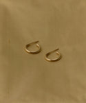 The Small Eloise Hoops from Jenni Kayne, crafted in 14k gold, rest parallel with a slight gap on a light brown fabric backdrop, embodying the timeless elegance of heirloom jewelry.